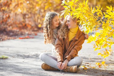 Sonbahar arka planında birlikte yürüyen iki güzel kız kardeş. Neşeli kızlar. Sonbahar kavramı.