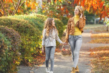Sonbahar arka planında birlikte yürüyen iki güzel kız kardeş. Neşeli kızlar. Sonbahar kavramı.