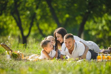 Piknikteki sevimli aile. Anne ve baba parkta çocuklarıyla oynuyorlar..