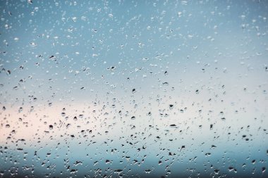 Pencereye yağmur damlaları. Bardakta su var. Koşan damla. Arkaplan kavramsal.