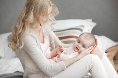 Küçük bebeği olan genç bir anne. Anne tatlı çocuğunu kucağında tutuyor. Annelik kavramı.