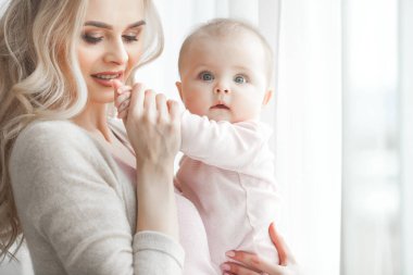 Küçük bebeği olan genç bir anne. Anne tatlı çocuğunu kucağında tutuyor. Annelik kavramı.