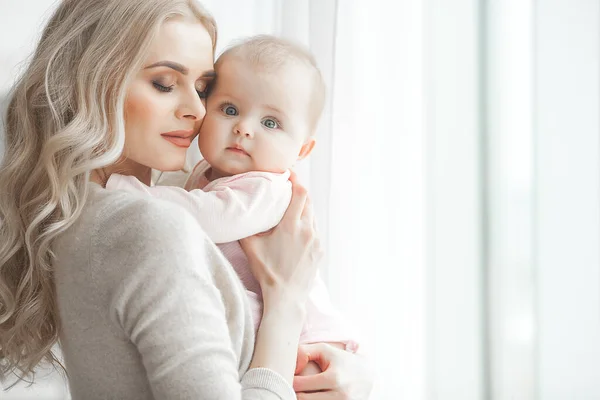 Küçük bebeği olan genç bir anne. Anne tatlı çocuğunu kucağında tutuyor. Annelik kavramı.