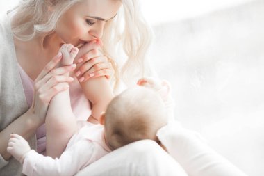 Küçük bebeği olan genç bir anne. Anne tatlı çocuğunu kucağında tutuyor. Annelik kavramı.