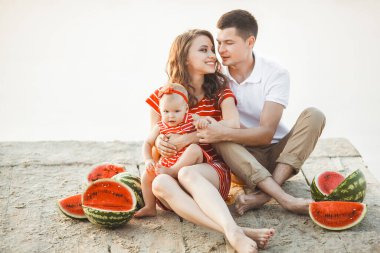 Kumsalda gün batımında sevimli bir aile. Yaz tatili. Aile birlikte eğleniyor..