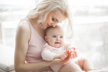 Küçük bebeği olan genç bir anne. Anne tatlı çocuğunu kucağında tutuyor. Annelik kavramı.