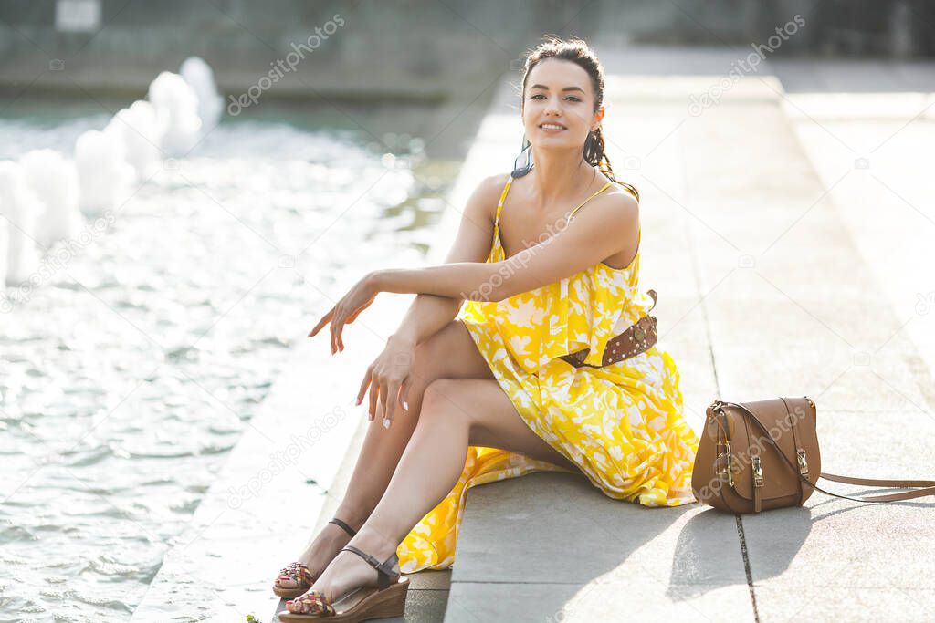 Young very beautiful woman outdoors on summertime. Attractive young lady near the fountain.