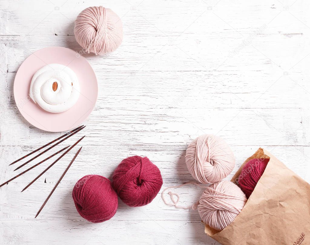 Pink and red yarn for knitting on a white wooden table
