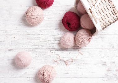 Hasır sepetteki iplik beyaz ahşap arka planda.