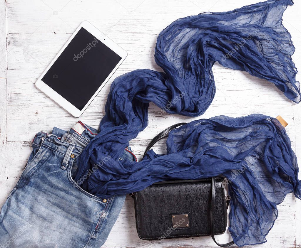 Set of womans items including scarf, tablet, handbag and jeans.