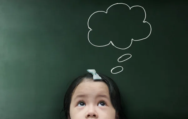 Little girl looking up over blackboard — Stock Photo, Image