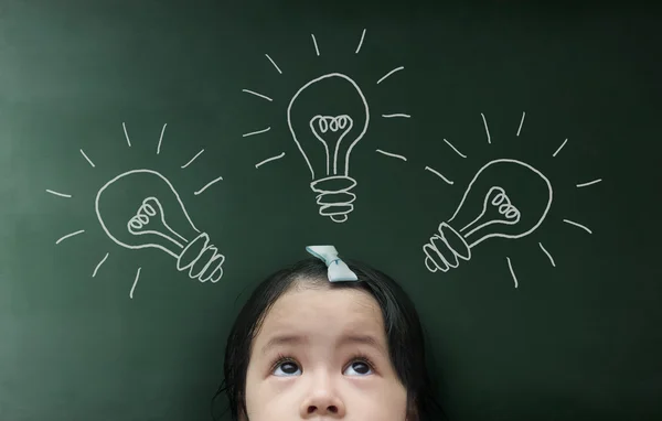 Little girl looking up over blackboard — Stock Photo, Image