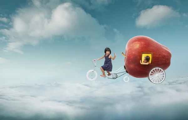 Giant apple and two girls over clouds — Stock Photo, Image