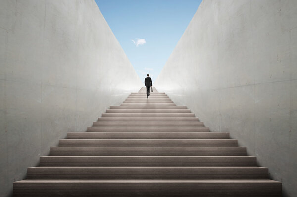 Концепция амбиций с бизнесменом, поднимающимся по лестнице
