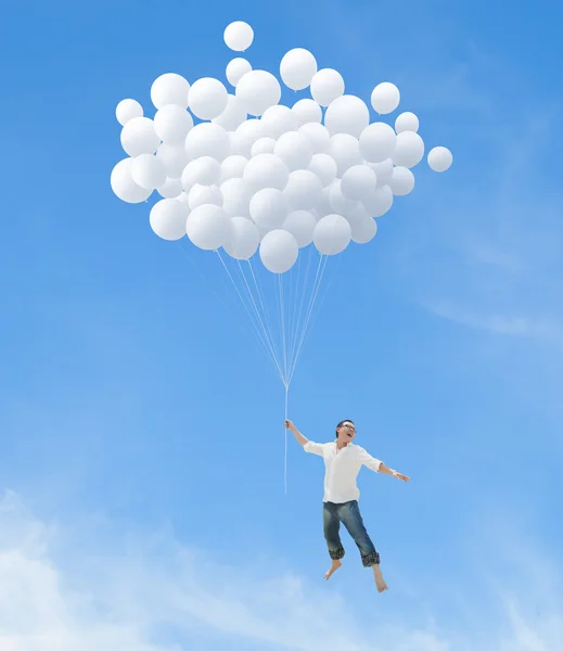 Homem voando em bando de balões brancos — Fotografia de Stock