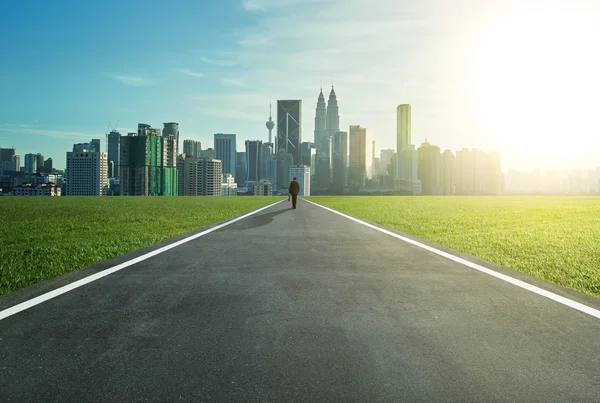 Man walking on the road towards city — Stockfoto