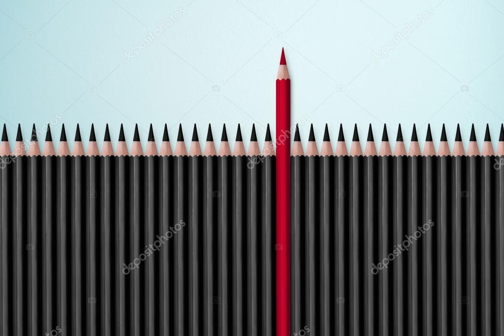 Red pencil standing out from crowd of plenty identical black fellows on white table. Leadership, uniqueness, independence, initiative, strategy, dissent, think different, business success concept