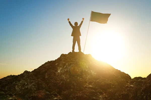 Silueta de hombre de negocios con bandera en la cima de la montaña — Foto de Stock