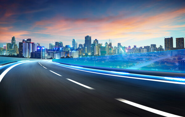 Blue neon light highway overpass motion blur with city skyline background , night scene .