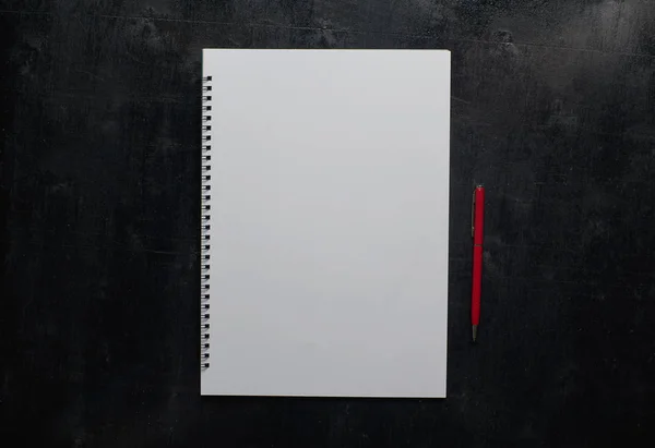 Notebook és piros toll a fekete asztal — Stock Fotó