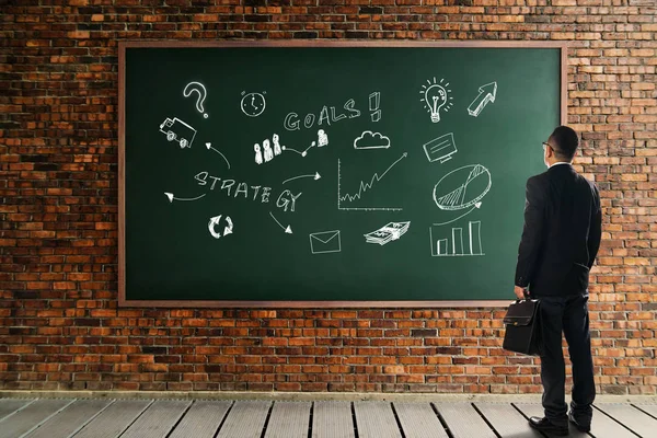 Businessman looking at chalkboard — Stock Photo, Image