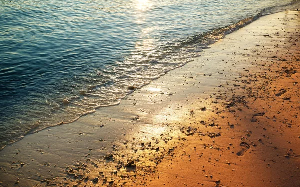 Amanhecer sobre a praia com pegadas — Fotografia de Stock