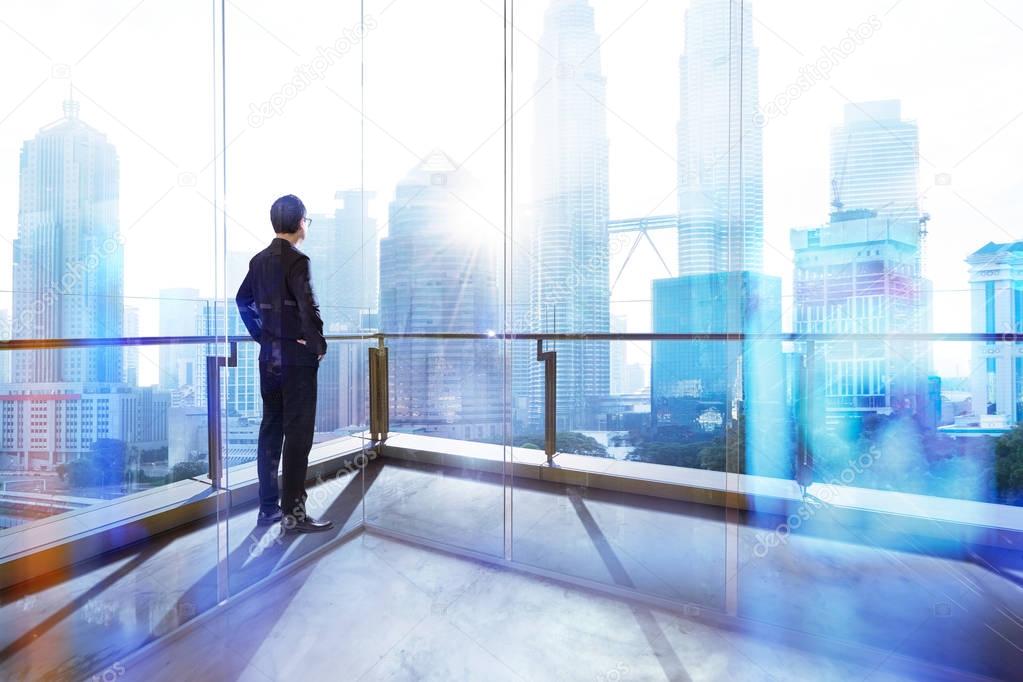 Young businessman looking out the city in the office