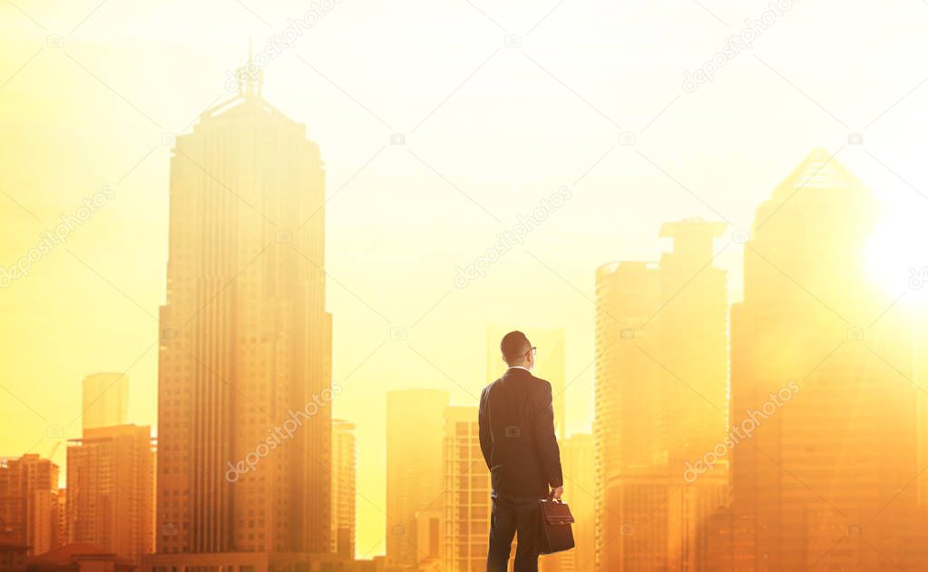 Young smart businessman looking at large city center
