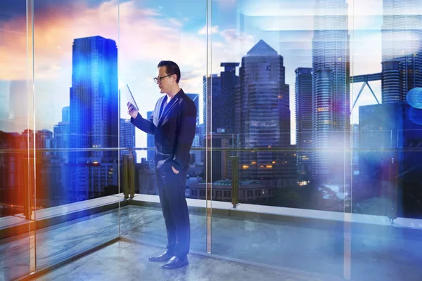 Un homme d'affaires utilise un support d'appareil numérique dans un bureau transparent moderne — Photo