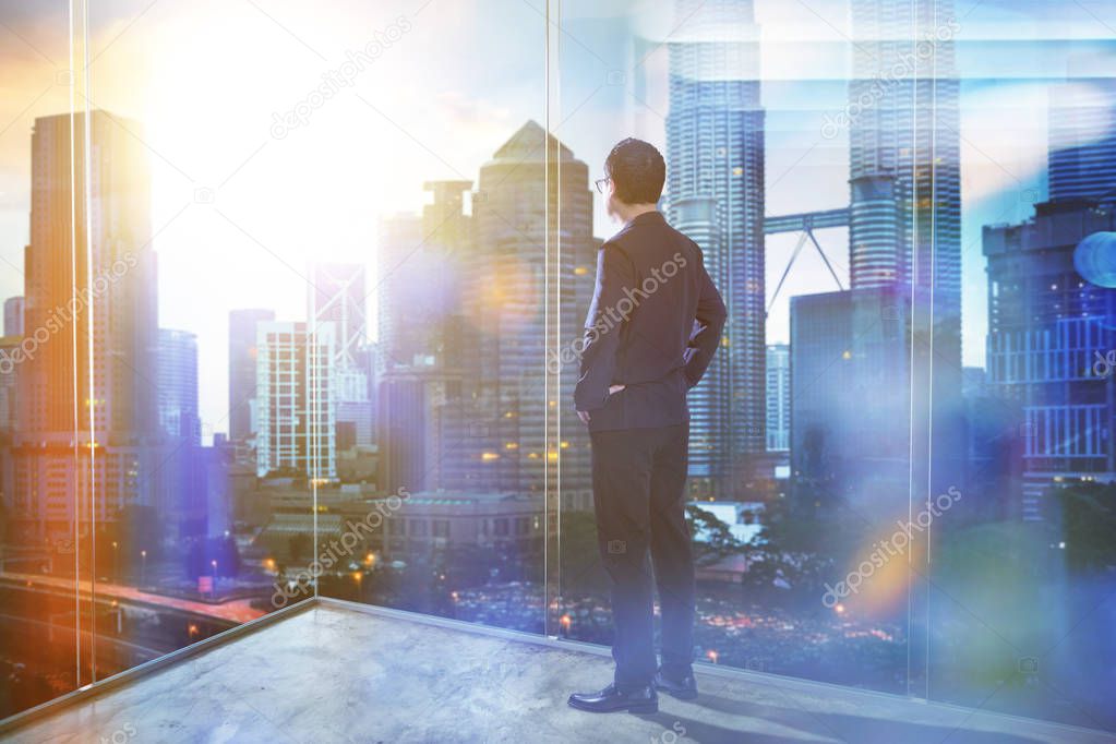 Young businessman looking out the city in the office