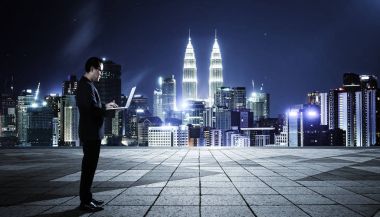 Cityscape arka plan ile gece sahne dizüstü kullanarak iş adamı .