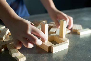bir blok ahşap kule oynayan çocuk 