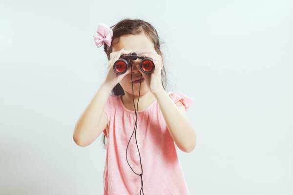 Красивая маленькая милая азиатская девочка с помощью телескопа смотрит вперед
 .
