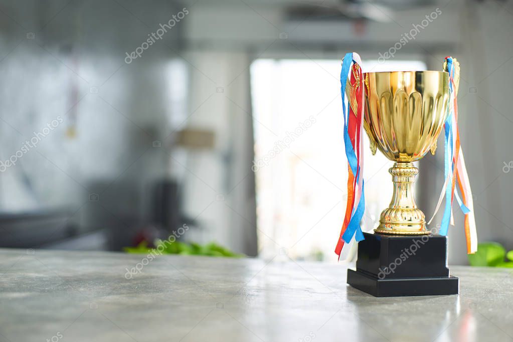 Golden trophy on the blur indoor background .
