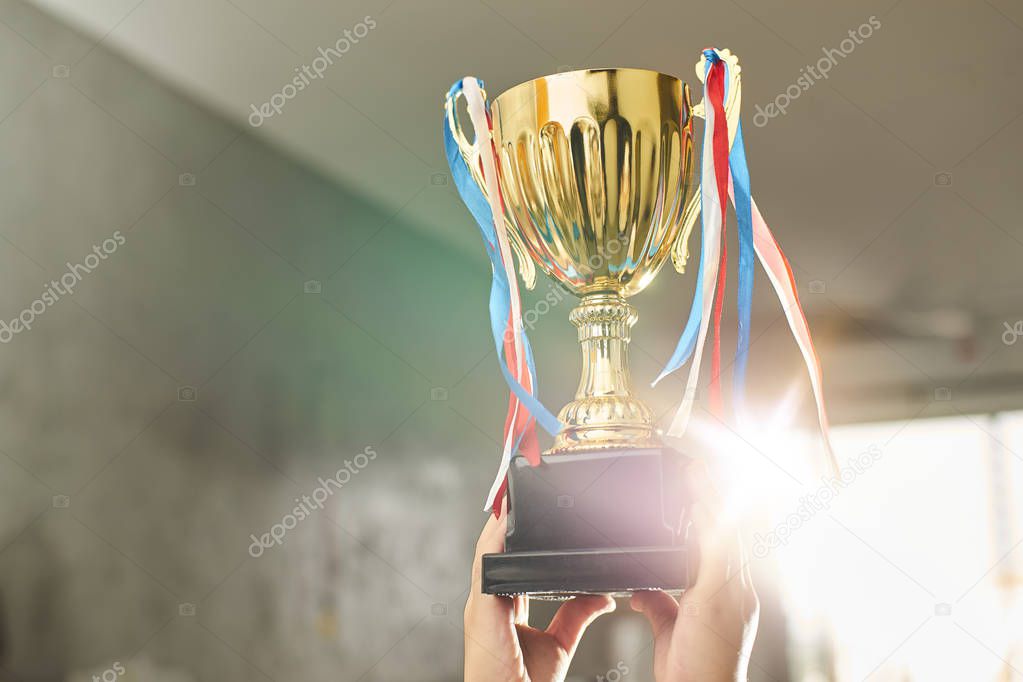 Young athlete holding up a gold trophy cup with space ready for your trophy design.