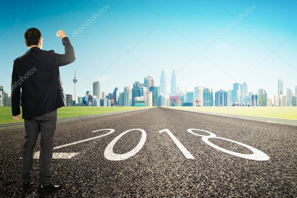 2018 new year ,young businessman cheer with city skyline background . Refresh and hope concept .