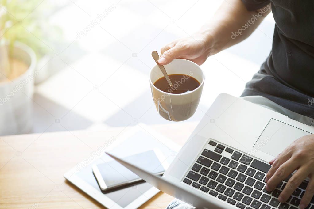 Coffee in businessman hand with Laptop ,digital tablet,smartphone and coffee .