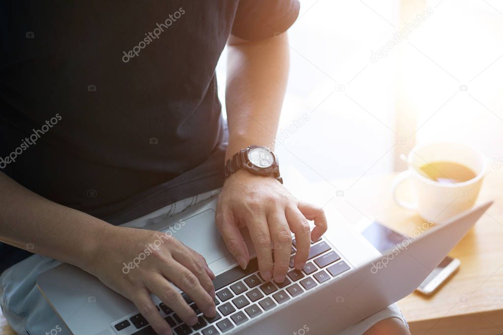 Laptop in businessman hand with smartphone and coffee .