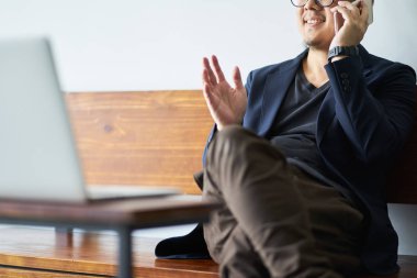 İşadamı oturmak belgili tanımlık laptop önünde smartphone kullanarak ahşap sandalye.