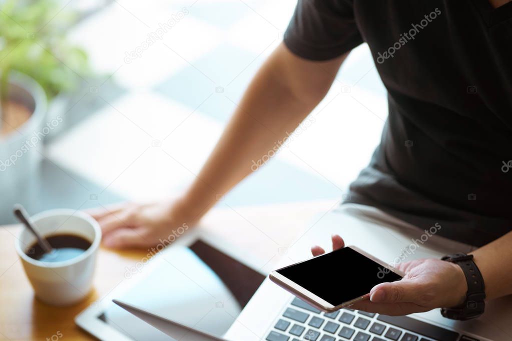 Smartphone in young man hand with digital tablet and coffee , selective focusing .