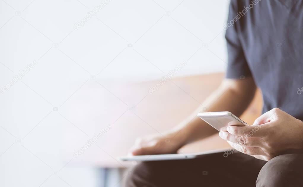 Smartphone in young man hand with digital tablet , selective focusing .