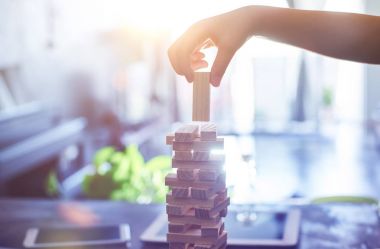 Bir blok ahşap oynayan çocuk el oyun güneş parlama ile mimari projesinin kule ve arka plan bulanıklık. Odaklanarak seçili .