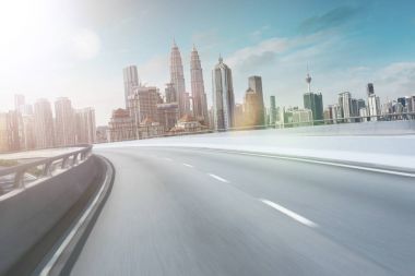 Hareket curvy üstgeçidin asfalt Otoban yol modern cityscape silüeti manzaralı. Sunrise sahne .