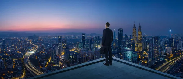 都市の景観景色眺めて屋上の上に立っての実業家 夜のシーン — ストック写真