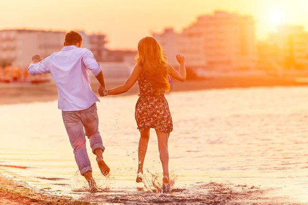 Rear view of happy couple running in summer on the beach in a tropical place. Two lovers in vacation in an idyllic nature scene sharing positive feelings and emotions. Magic moments  of loving hearts.