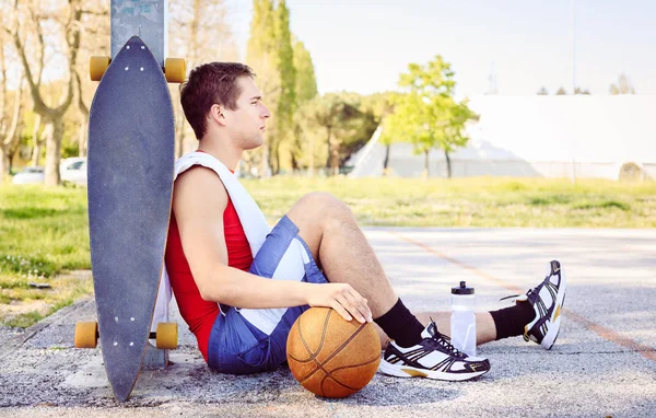 Sporcu arkadaşları ile maçtan sonra bir basketbol sahası içinde oturuyor. Sarışın adam konsantrasyonu spor Park yapmak için arama. Eğitim ve egzersiz vintage filtresiyle koşu fitness kavramı — Stok fotoğraf