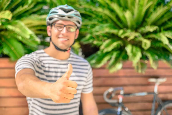 Hipster guy gör tummen efter en ride cykel runt stan. Optimistiska människan visar hans attityd att göra sport och använda alternativ transport. Aktiv person njuter av vardagen stunder. — Stockfoto