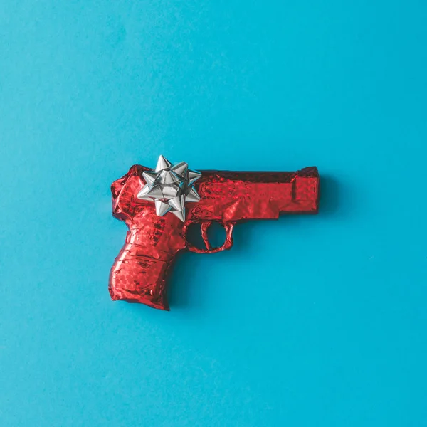 Gun wrapped in red paper with bow — Stock Photo, Image