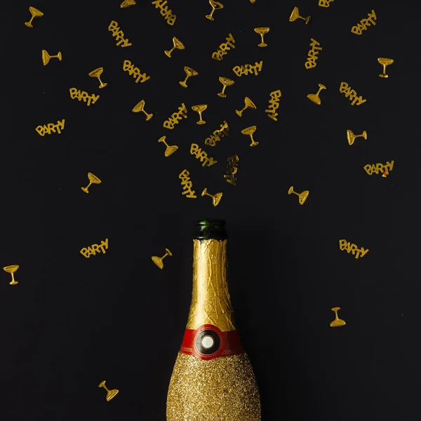 Gouden champagne partij fles met confetti op donkere achtergrond. — Stockfoto