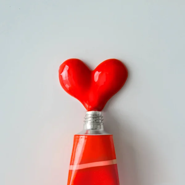 Red paint in shape of heart with tube — Stock Photo, Image